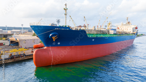 Oil tanker ship under maintenance crane at dry dock concept maintenance service working in the sea. Insurance and Maintenance Cargo Ship concept. Service maintenance Insurance