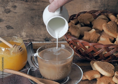 Food background.Healthy homemade food.Hands of an elderly woman pour milk into a cup of tea.