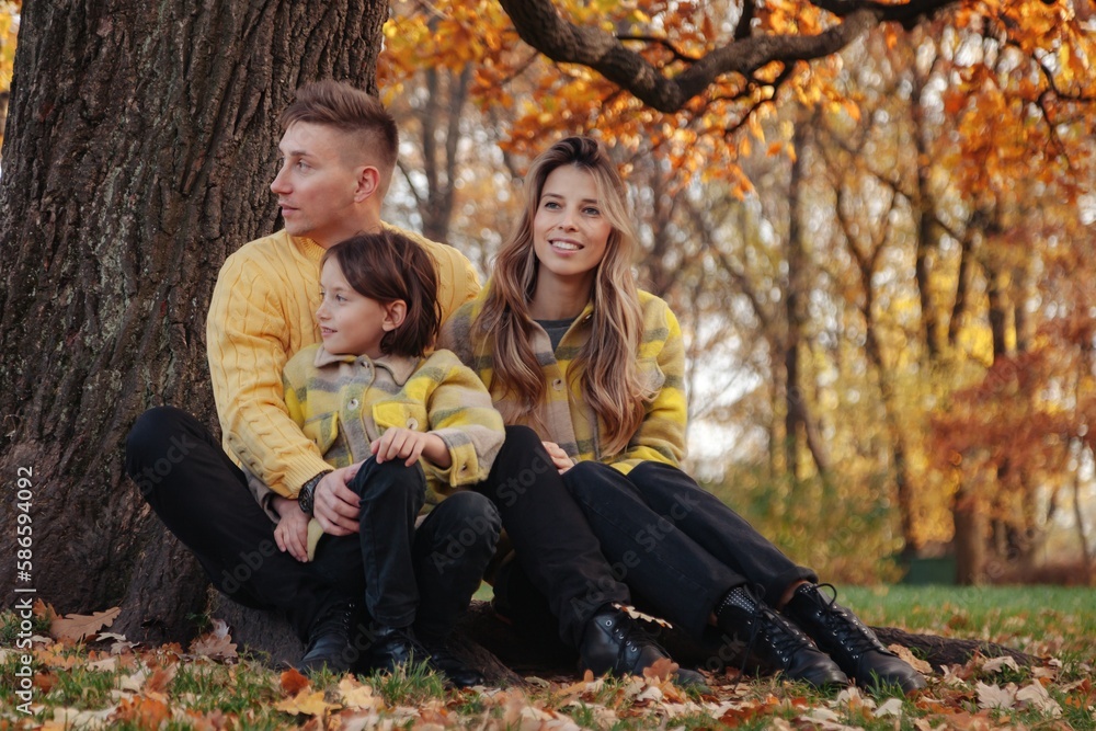 Young family in yellow clothes in autumn park spend time together outdoors, happy hugging having fun. Mom, dad and daughter in fall nature. Concept of parenthood and family leisure. Copy ad text space