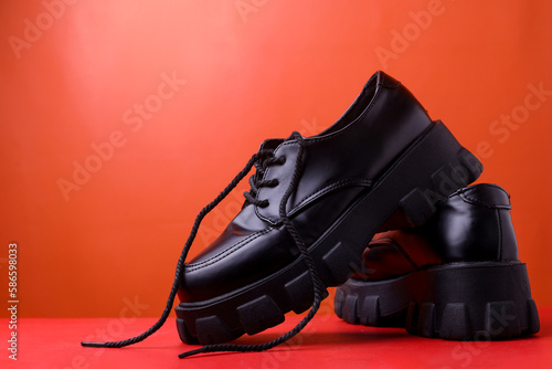 side of a pair of black leather men's shoes isolated on a red background
