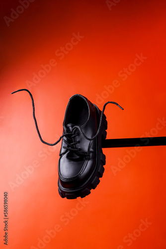 Flying black leather womens isolated on red background. Fashionable stylish casual shoes. Creative minimalist layout with footwear Mock up for your design Advertising for shoe store