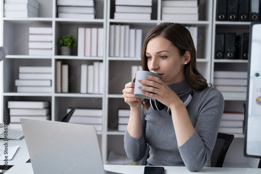 Elegent young businesswoman drinking coffee while sitting at her office desk. Elegent young businesswoman drinking coffee while sitting at her office desk.