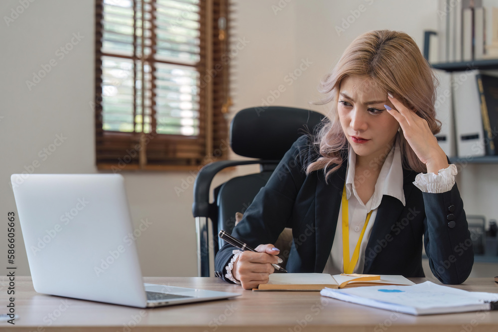 Businesswoman tired and stressed with overworked at desk, woman asian with worried not idea with graph analysis laptop and at office Businesswoman tired and stressed with overworked at desk, woman asian with worried not idea with graph analysis laptop and at office