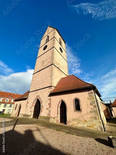 Stunning Low-Angle Wide Perspective of the Majestic Saint-Jean-Baptiste Church of Wattwiller Against a Brilliant Azure Sky, in Haut-Rhin, Alsace, France, with some clouds photo