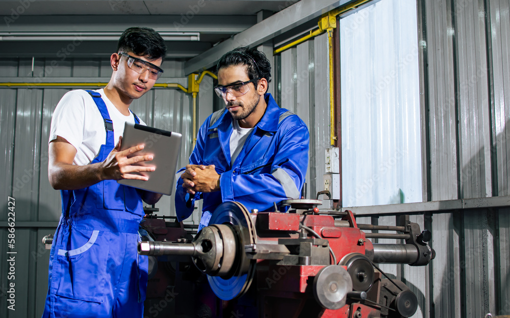 Portrait two handsome male mechanics wearing uniform, using machine for fix, repair car or automobile components, teamwork helping, working in car maintenance service center or shop. Industry Concept. Portrait two handsome male mechanics wearing uniform, using machine for fix, repair car or automobile components, teamwork helping, working in car maintenance service center or shop. Industry Concept.
