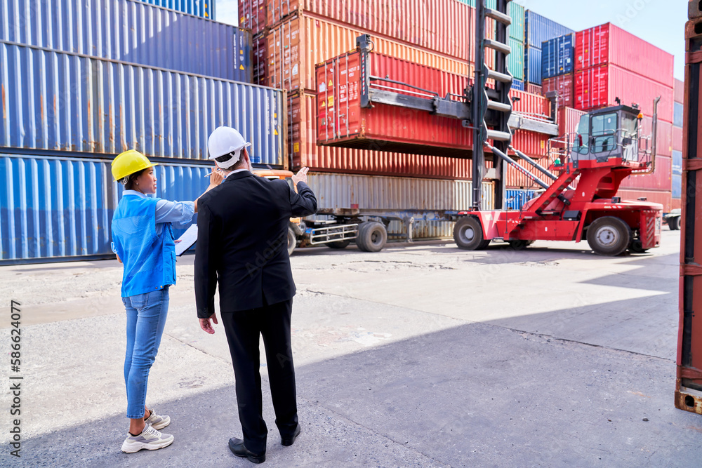 Manager in black suit order to foreman woman to move container box for stacking in logistic site