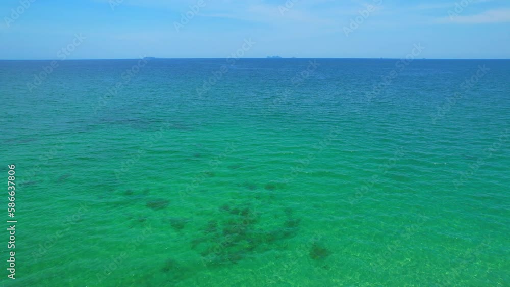 The water is a vibrant shade of blue-green, darker shades of blue as it extends further out to sea. Small waves break gently on the shore, leaving behind intricate patterns in the sand. Drone
The water is a vibrant shade of blue-green, darker shades of blue as it extends further out to sea. Small waves break gently on the shore, leaving behind intricate patterns in the sand. Drone