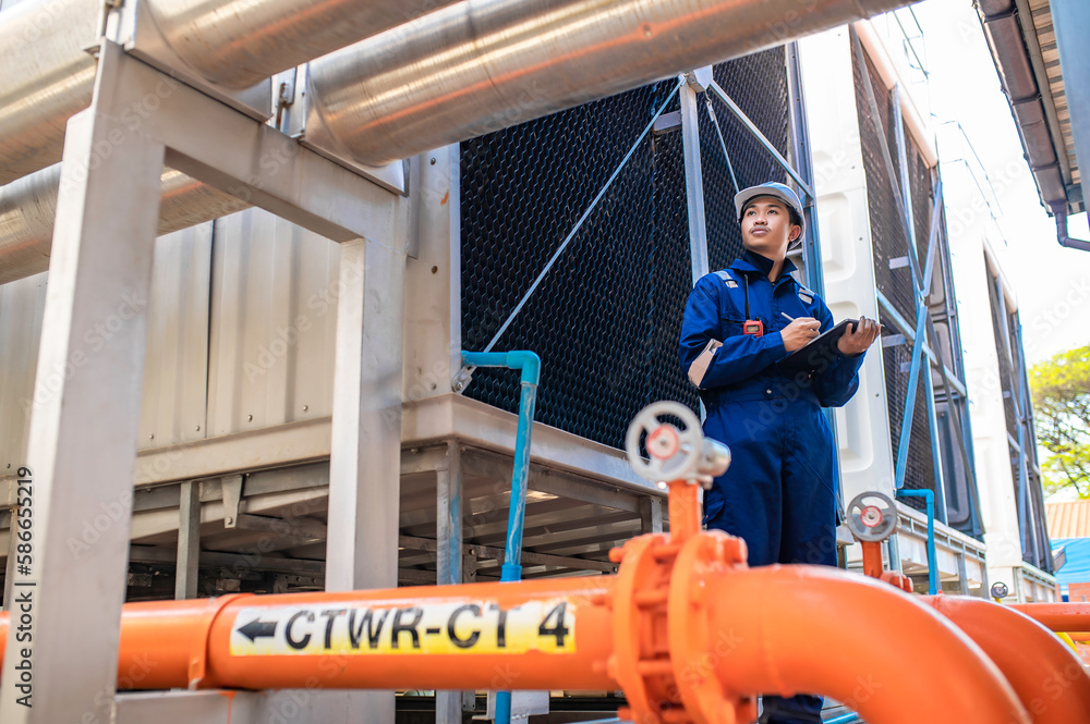 Young engineer working at large factory,Technician in protective uniform and with hardhat checking temperature in pipes Young engineer working at large factory,Technician in protective uniform and with hardhat checking temperature in pipes