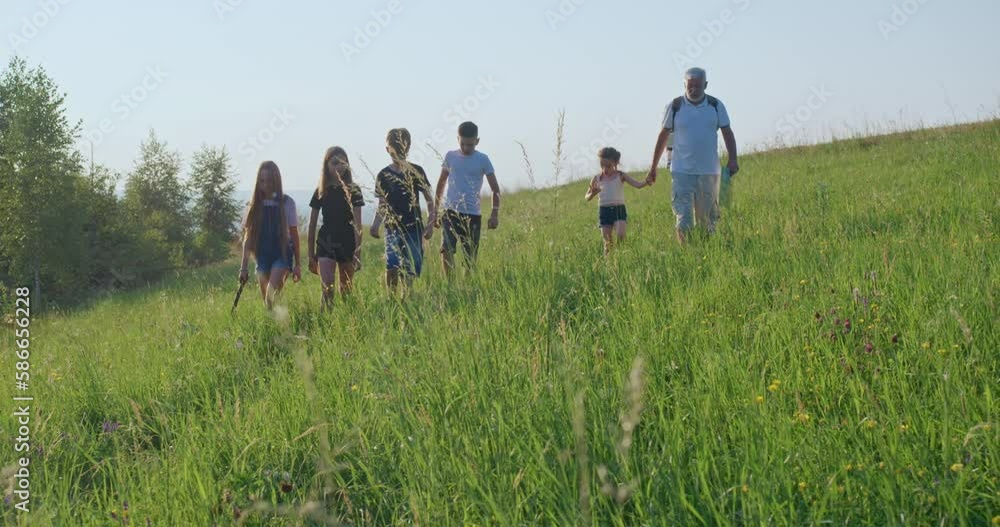 Front view of children going, approaching, girl with long hair jack russel terrier leading, playing with stick, old man map holding. Tourists enjoying nature. Concept of hiking. Front view of children going, approaching, girl with long hair jack russel terrier leading, playing with stick, old man map holding. Tourists enjoying nature. Concept of hiking.