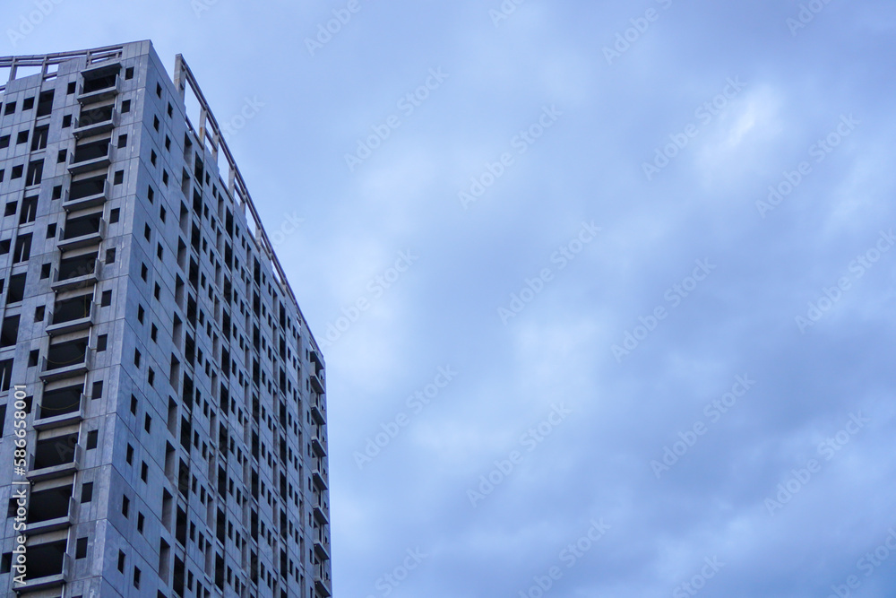 An unfinished building stands tall against a bleak grey sky, devoid of any signs of life or activity, with its empty spaces waiting to be filled An unfinished building stands tall against a bleak grey sky, devoid of any signs of life or activity, with its empty spaces waiting to be filled