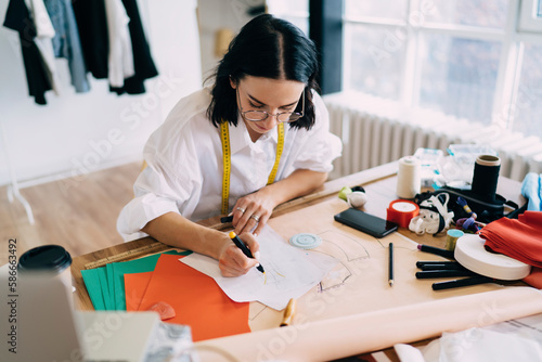 Concentrated female artist drawing sketches of new clothes