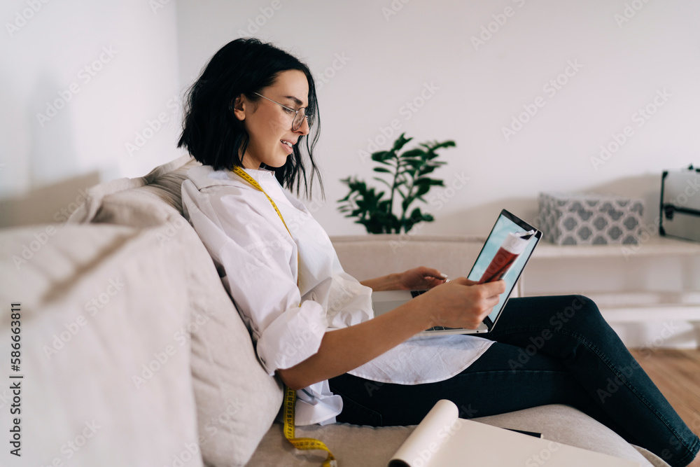 Focused female designer with computer reading magazine Focused female designer with computer reading magazine