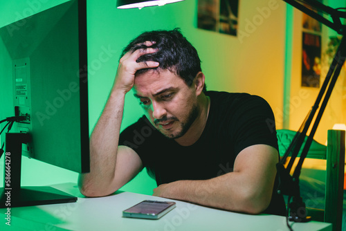Young latin man seeing how he loses in all the bets he made during the day.