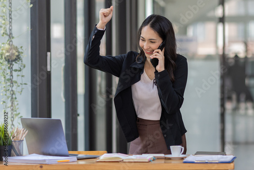 Portrait excited young indian asian woman happy smile in formal shirt using laptop trading or chatting at work in workplace finance business concept.