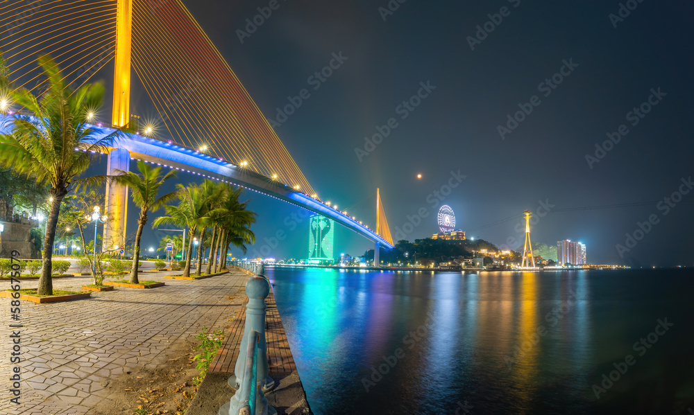Fototapeta premium Colorful night view of Bai Chay Bridge, connecting two parts of Ha Long City, Hon Gai City and Bai Chay City through Cua Luc Bay.