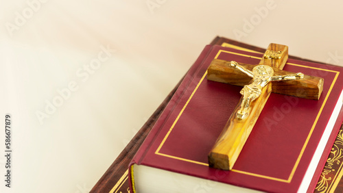 Religion composition with wooden crucifix with closed red Christian bibles on a light gradient background with divine light. Bible and Scripture Study. Religious church holidays. Copy space