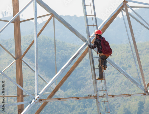 worker climbing on transmission tower