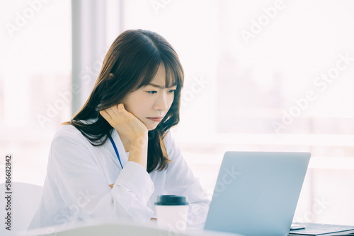 困った表情でパソコンを使う日本人女性ビジネスマン