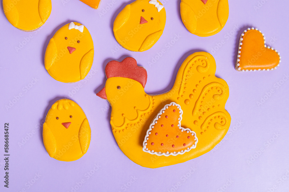 Easter gingerbread with icing on purple background. Gingerbreads in the form of chickens and hearts. Easter treats Easter gingerbread with icing on purple background. Gingerbreads in the form of chickens and hearts. Easter treats