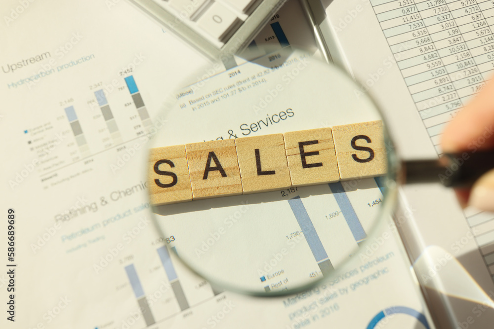 Hand of person holding magnifier glass above word sales Hand of person holding magnifier glass above word sales