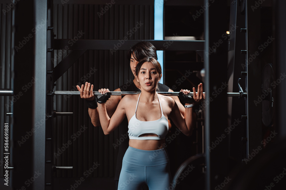 Woman working out Bodybuilder with coaching assistance to support weights at the gym. bodybuilder doing exercises with barbell. training sport healthy lifestyle bodybuilding... Woman working out Bodybuilder with coaching assistance to support weights at the gym. bodybuilder doing exercises with barbell. training sport healthy lifestyle bodybuilding...