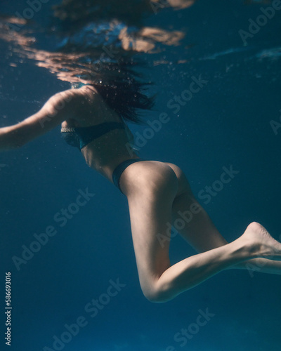 young girl in swimsuit swims underwater
