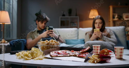Fotografie Bored young couple is frustrated after hard day, sitting in front of tv but scro