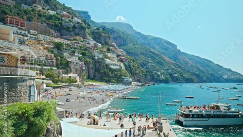 Amazing view of a ship arriving and departing in Positano, Amalfi coast. People getting on board a big vessel surrounded by small boats and beautiful colorful houses. photo