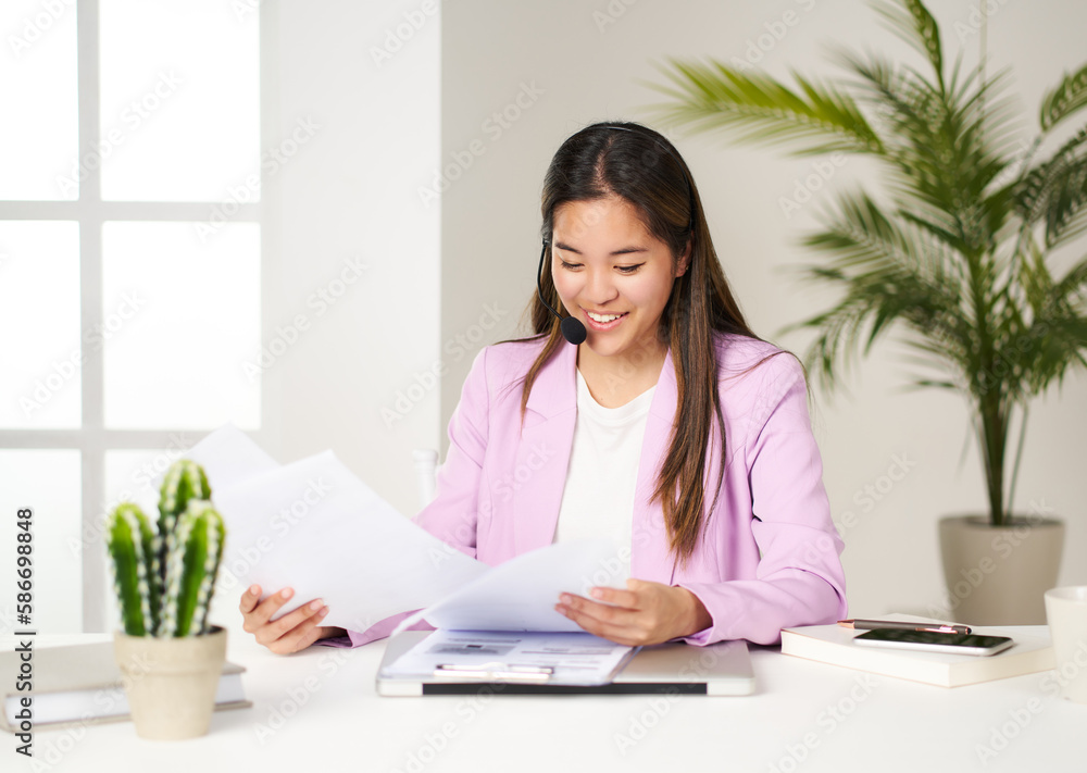 portrait of asian business woman in pink jacket checking invoices at coworking