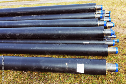 A pile of water pipes with thermal insulation in a meadow