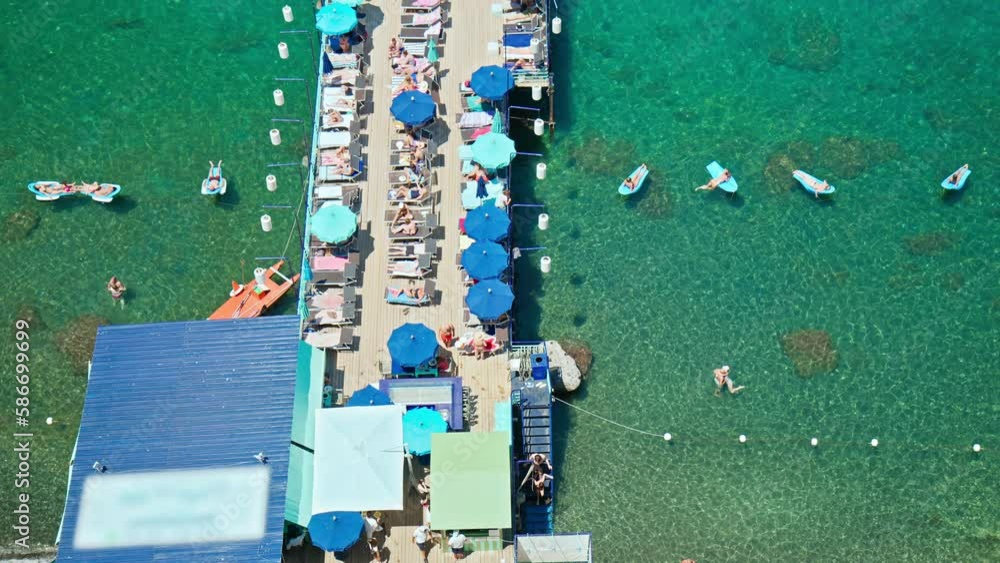 People swim and rest at a sheltered bay and pebbly strand backed by ...