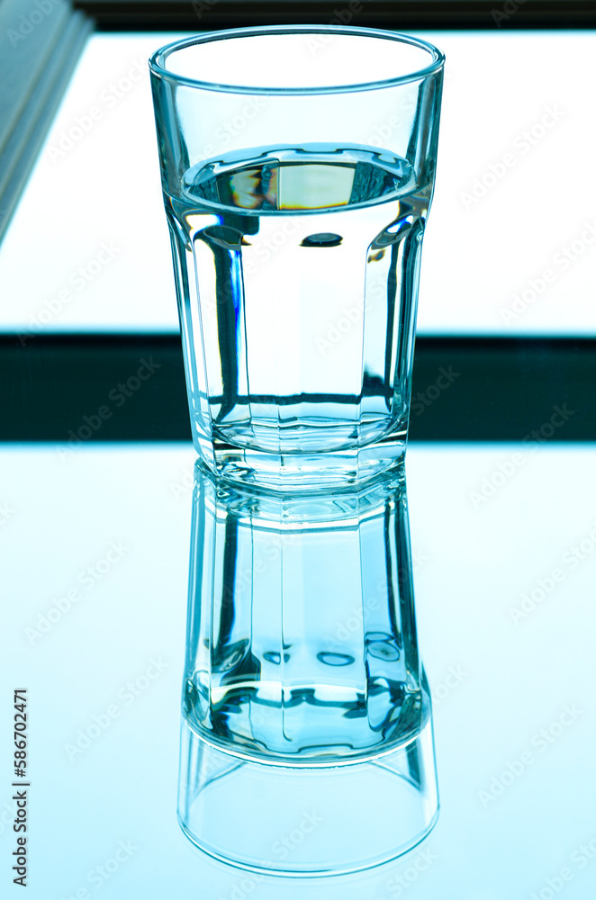 Reflection of a glass of spring water in the mirror Reflection of a glass of spring water in the mirror