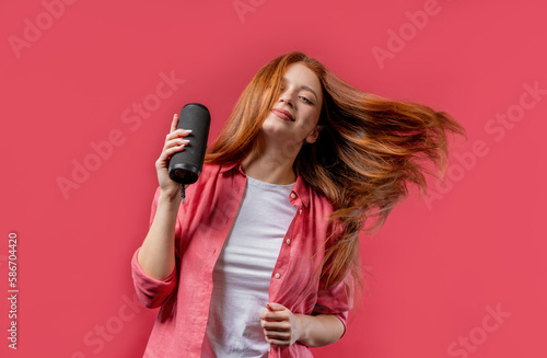 Young woman listening to music by wireless portable speaker, dancing rich hair