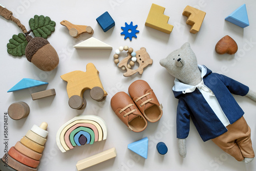 toys for the baby from ecological materials, wooden and homemade, top view and mall children's leather shoes and teddy bear