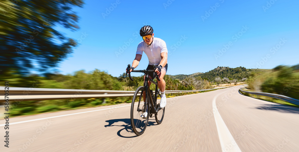 Man Adult on a racing bike climbing the hill at mediterranean sea landscape coastal road on mallorca balearic island