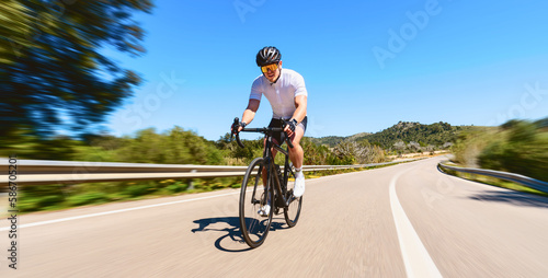 Obraz na płótnie Man Adult on a racing bike climbing the hill at mediterranean sea landscape coastal road on mallorca balearic island w salonie