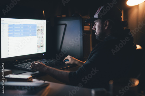 A man works at a computer in the light of a lamp