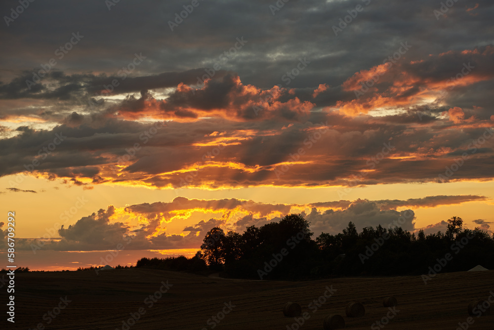 Unsettled red sky over fields and trees during sunset. Unsettled red sky over fields and trees during sunset.