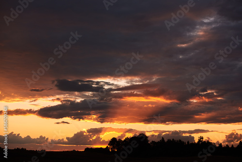 Unsettled red sky over fields and trees during sunset. © barytek
