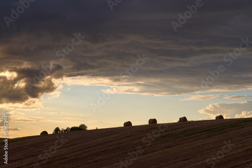 Contours of straw bales on a cloudy sky background