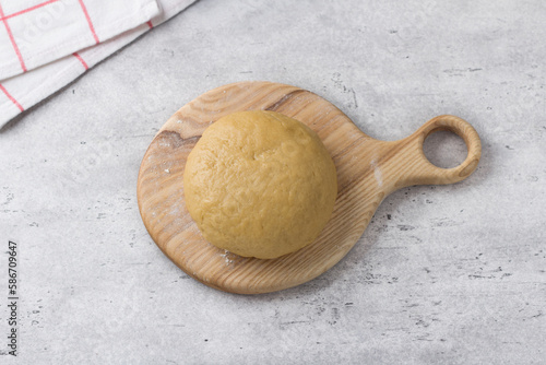 Wooden board with ready dough for koulourakya greek easter cookies with sesame seeds on gray textured background. Step by step instruction. Do it yourself. Step 5. Knead soft dough. photo