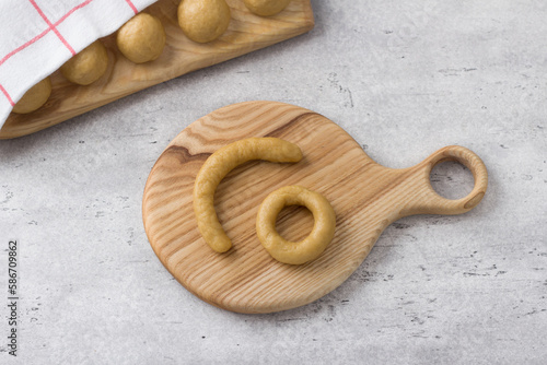 Raw dough pieces for Greek Easter cookies on a gray textured background. Step by step instruction. Do it yourself. Step 6. Roll a piece of dough into a sausage, connect the edges and form a ring photo