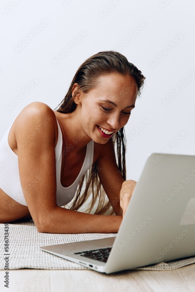 A woman lies on the floor at home and smiles with her teeth while looking at a laptop while chatting online and watching TV shows on her day off A woman lies on the floor at home and smiles with her teeth while looking at a laptop while chatting online and watching TV shows on her day off