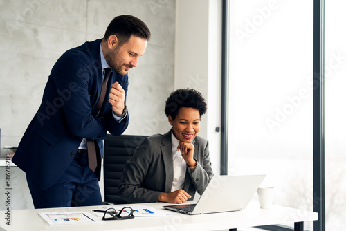 Handsome businessman and Afro American business woman working together in office at desk