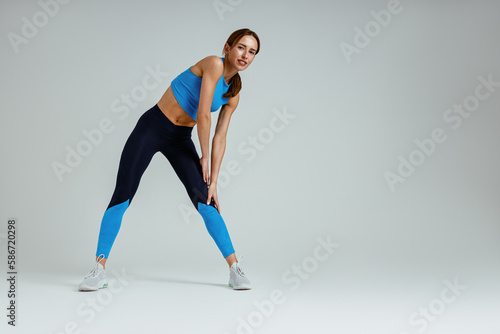 Smiling woman stretching her legs in studio before sports training or workout. High quality photo