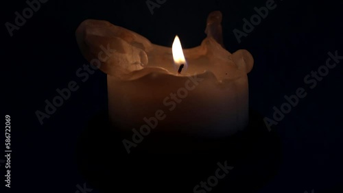 A gust of wind extinguishes the flame of the candle burning in the dark night.