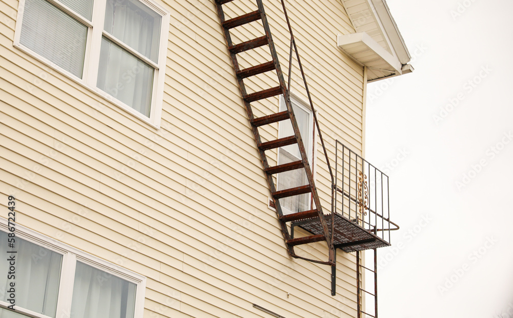 view of fire escapes on buildings and houses. A series of metal ladders and platforms are