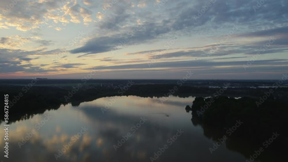 This drone video shows a beautiful lake surrounded by dense forest. The water on the lake is calm and transparent, reflecting the greenery of the trees and the blue sky. The shore of the lake is decor This drone video shows a beautiful lake surrounded by dense forest. The water on the lake is calm and transparent, reflecting the greenery of the trees and the blue sky. The shore of the lake is decor