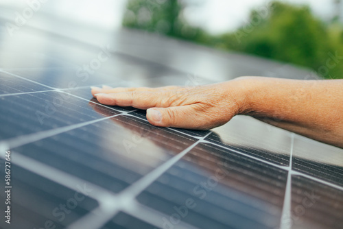 Close up of an young engineer hand is checking an operation of sun and cleanliness of photovoltaic solar panels on a sunset. Concept:renewable energy, technology, electricity, service, green, future