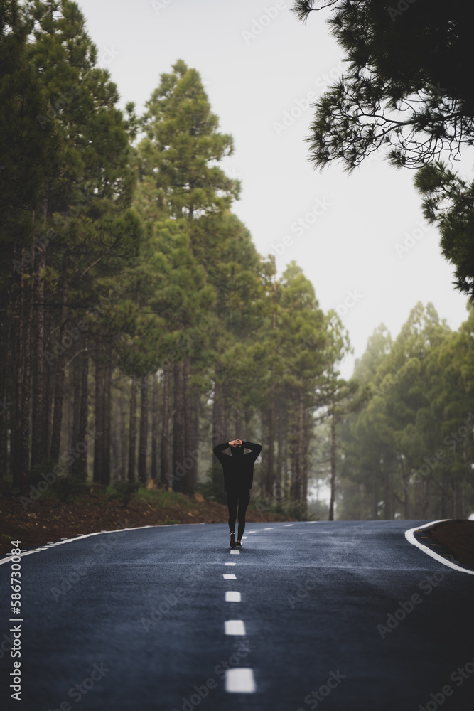 Stunning view of a girl walking on a road that crosses a beautiful forest. Pico de las Nieves, Gran Canaria, Canary Islands.